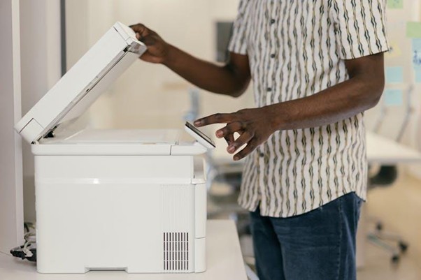 Persona che utilizza uno scanner multifunzione in un ambiente d'ufficio moderno.